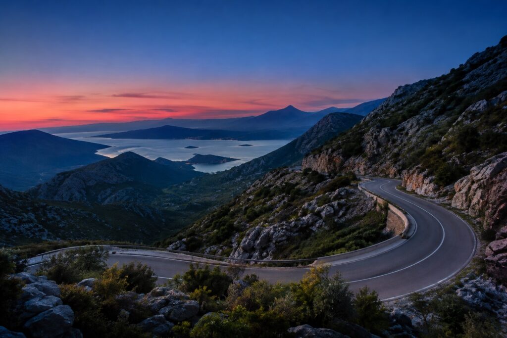 A winding mountain road beneath a blue twilight sky
