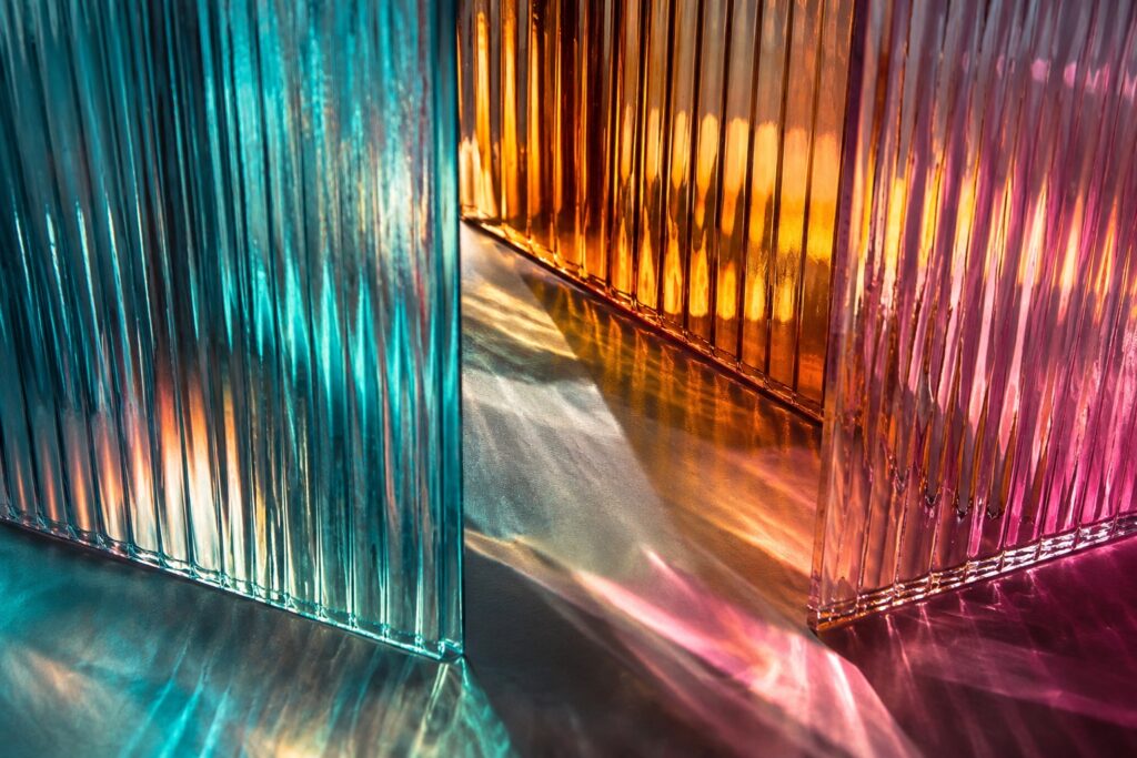 Overlapping ribbed glass panels refracting cyan, magenta and amber light